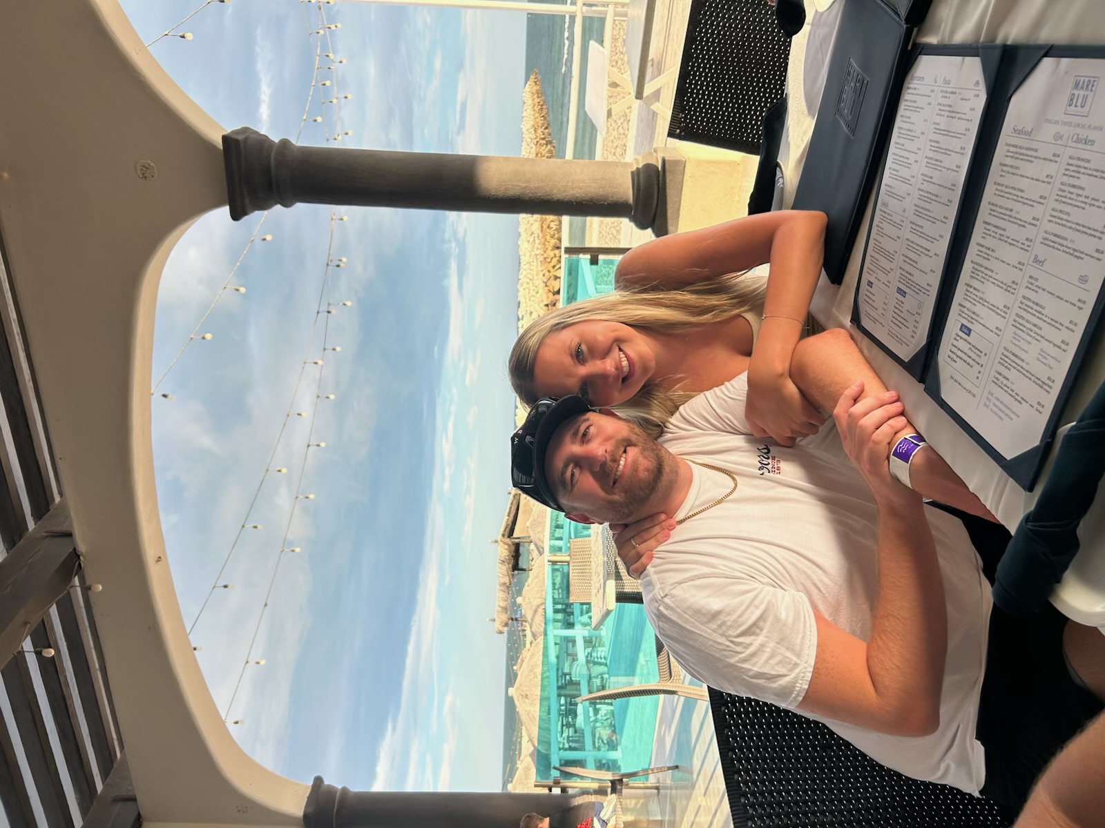 Couple at an oceanfront resort restaurant with an infinity pool and the sea behind them