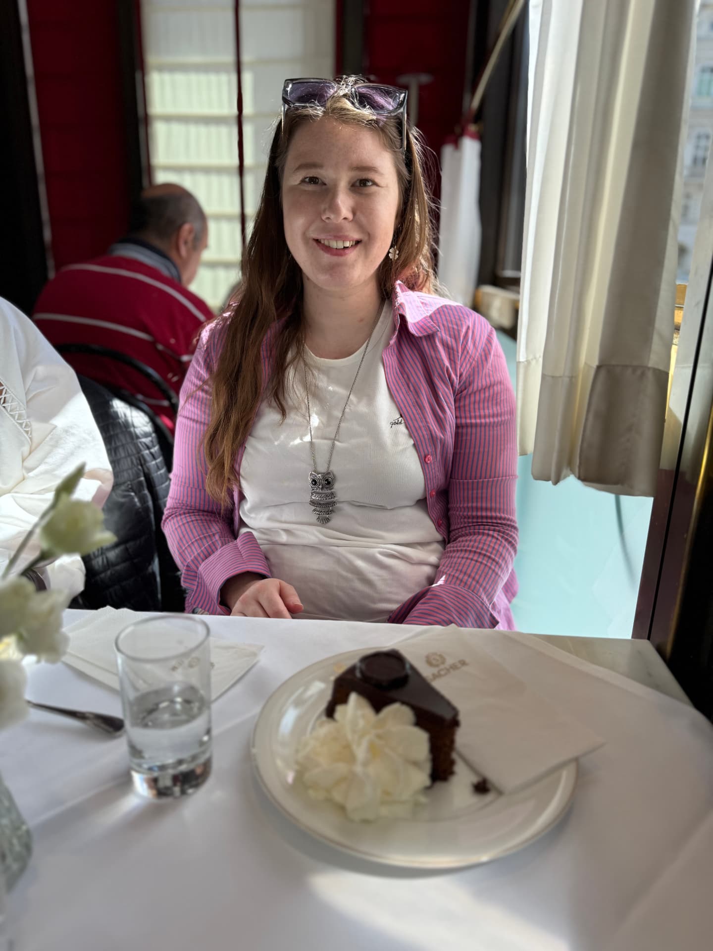 A slice of Sacher torte with whipped cream at a window table in Vienna