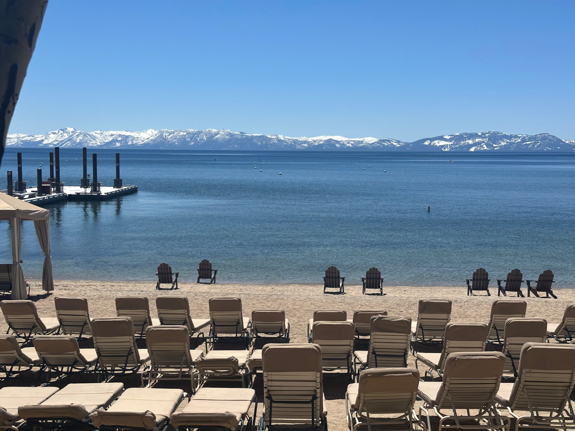 Lake Tahoe beach with loungers and snow-capped mountains across the water