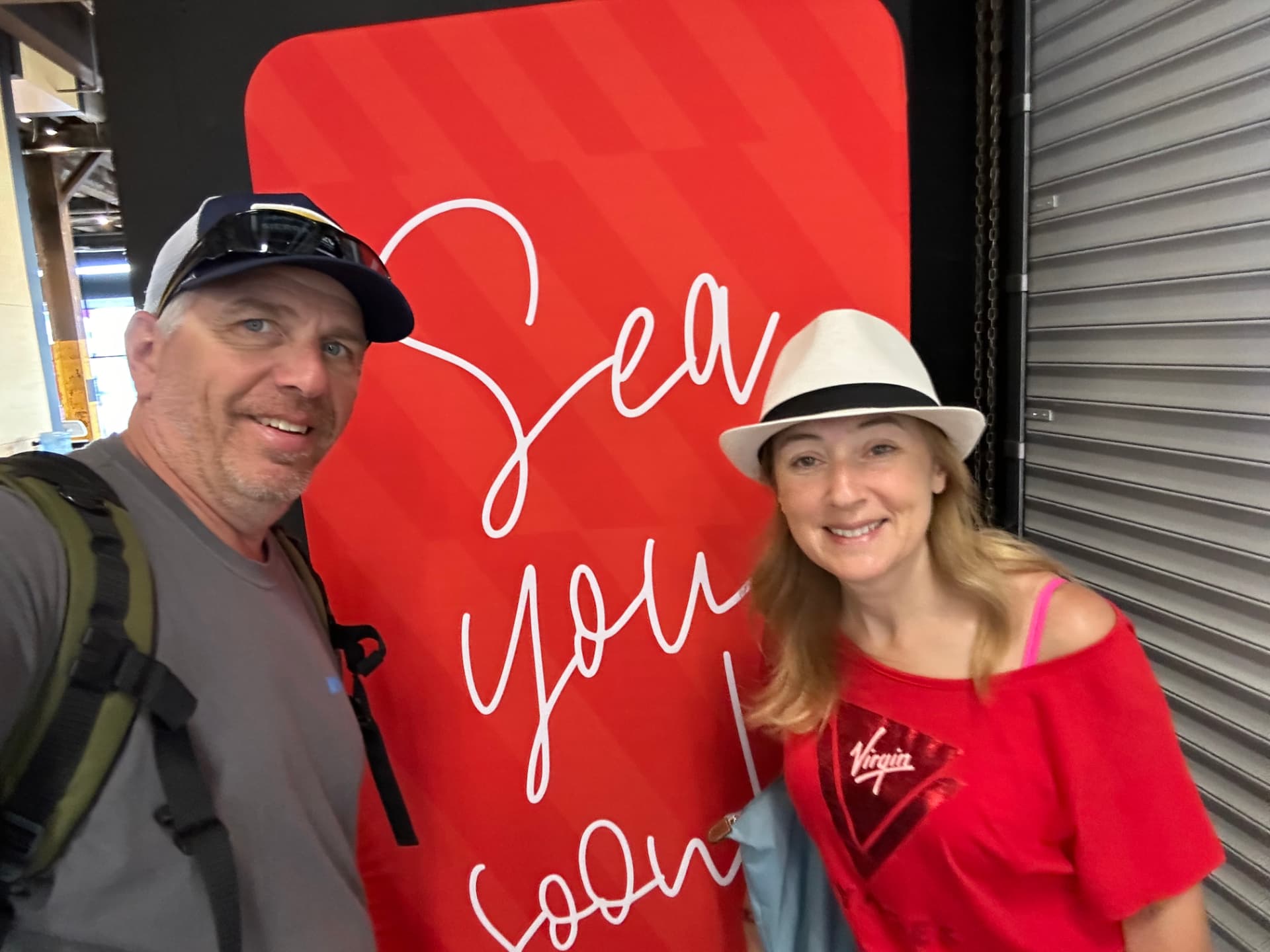 Natalia and her husband at the Virgin Voyages 'Sea you soon' terminal wall