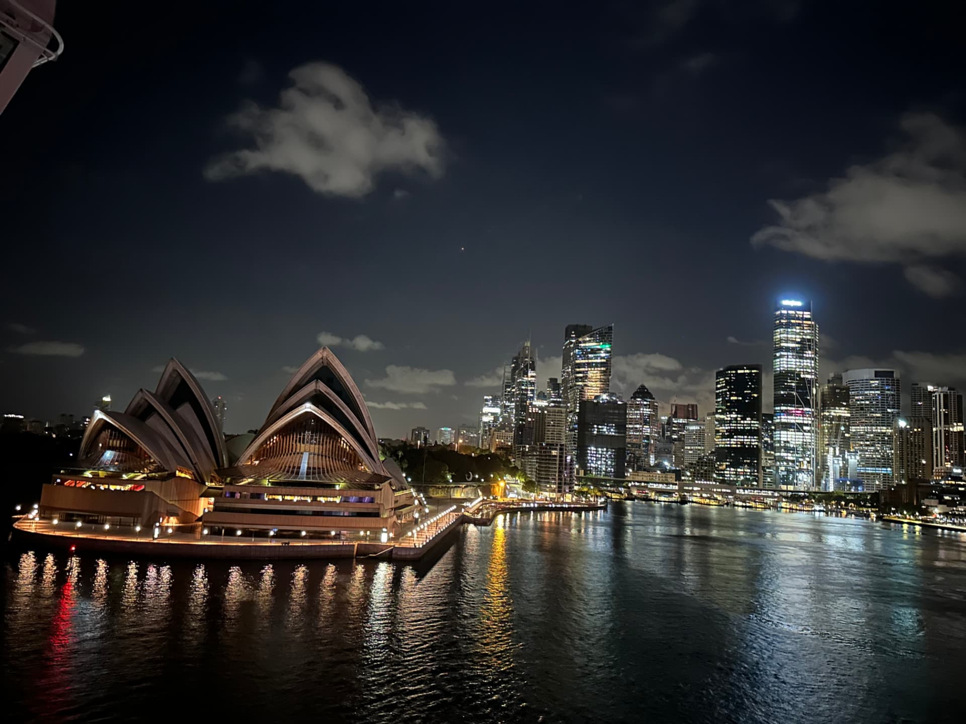 Sydney Opera House and skyline lit up at night from a cruise ship