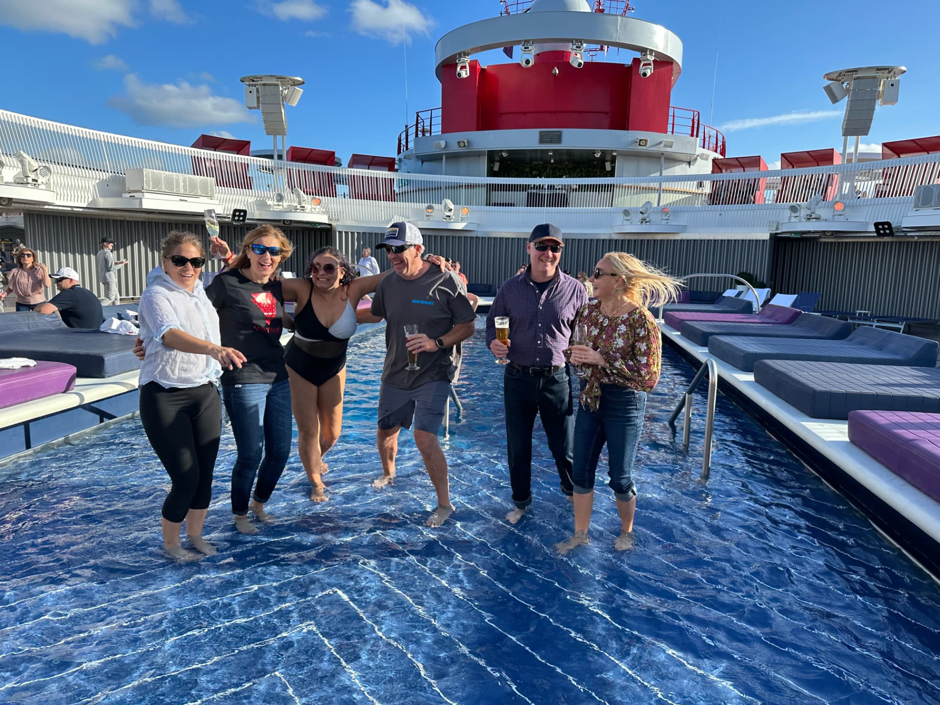Friends wading in the pool on a Virgin Voyages sun deck